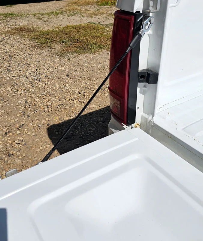 Tailgate cables shown installed on a white Chevy S10 truck