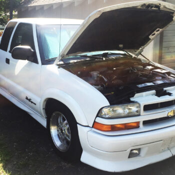 9404 hood strut kit installed on white and black chevy truck