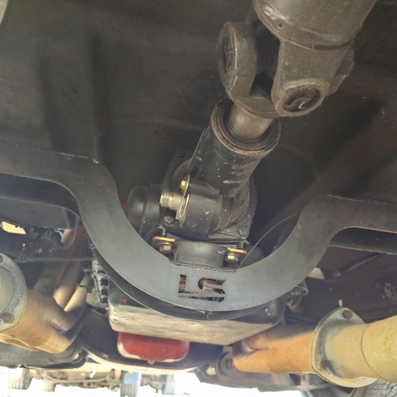 Transmission crossmember shown installed under a classic GM truck frame